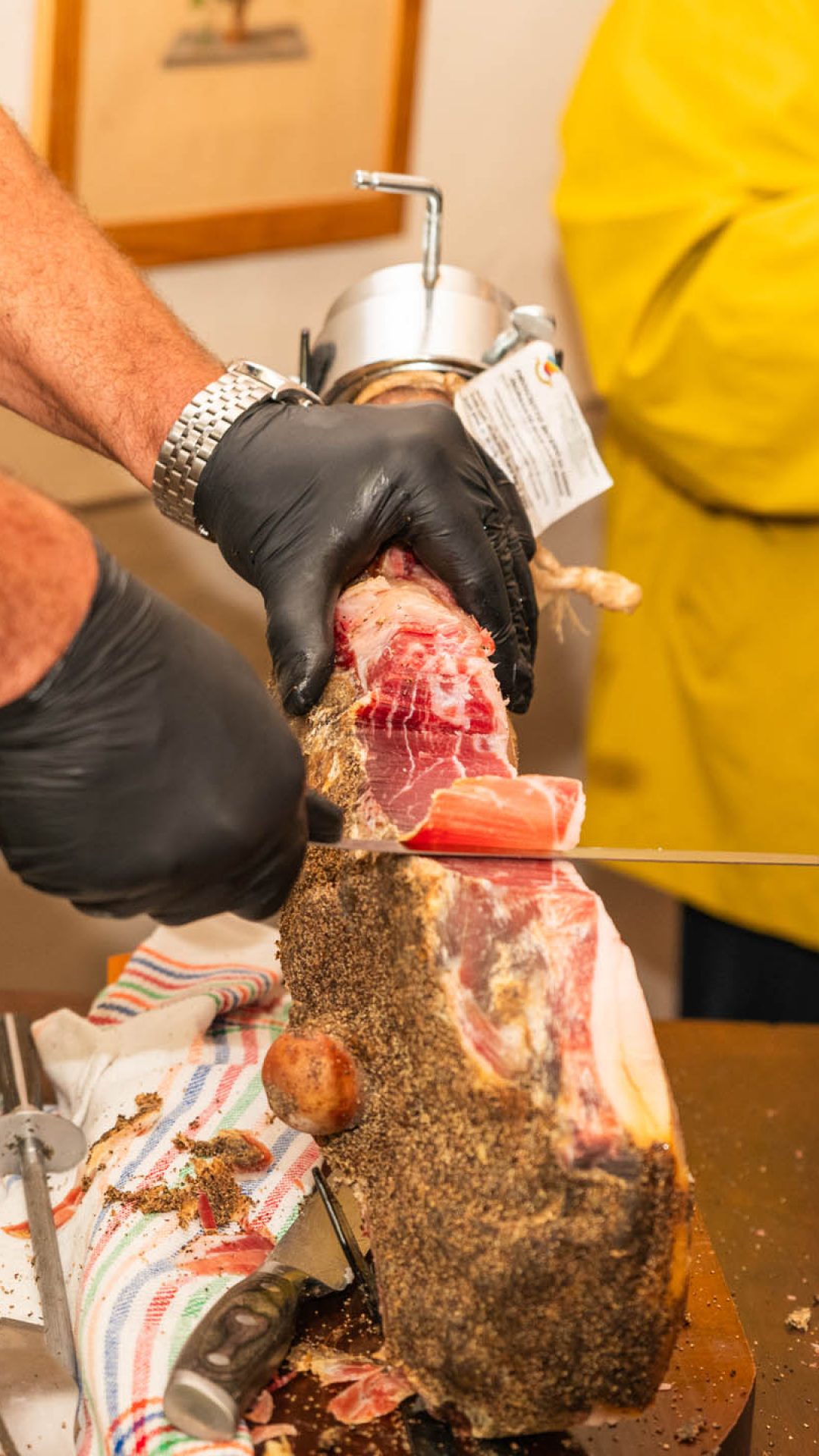 Foto fatta a uomo che affetta il prosciutto a a mano