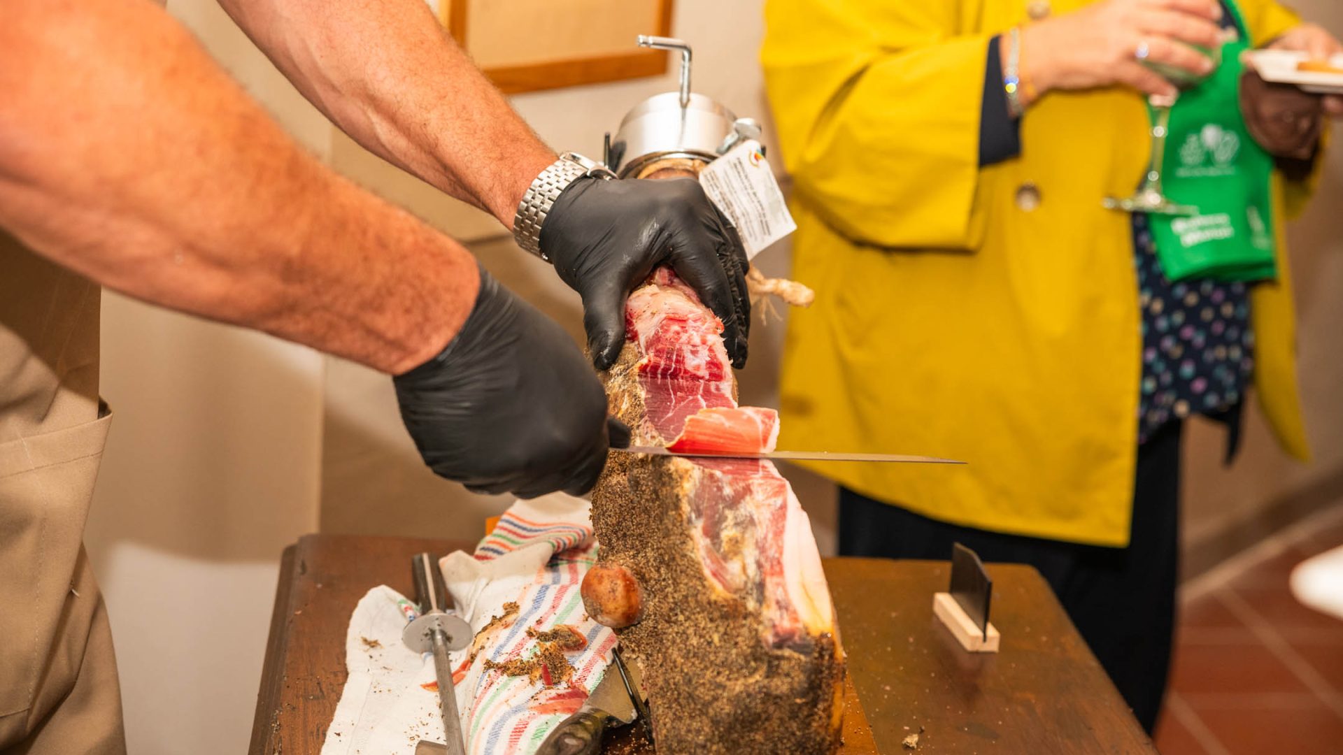 Foto fatta a uomo che affetta il prosciutto a a mano